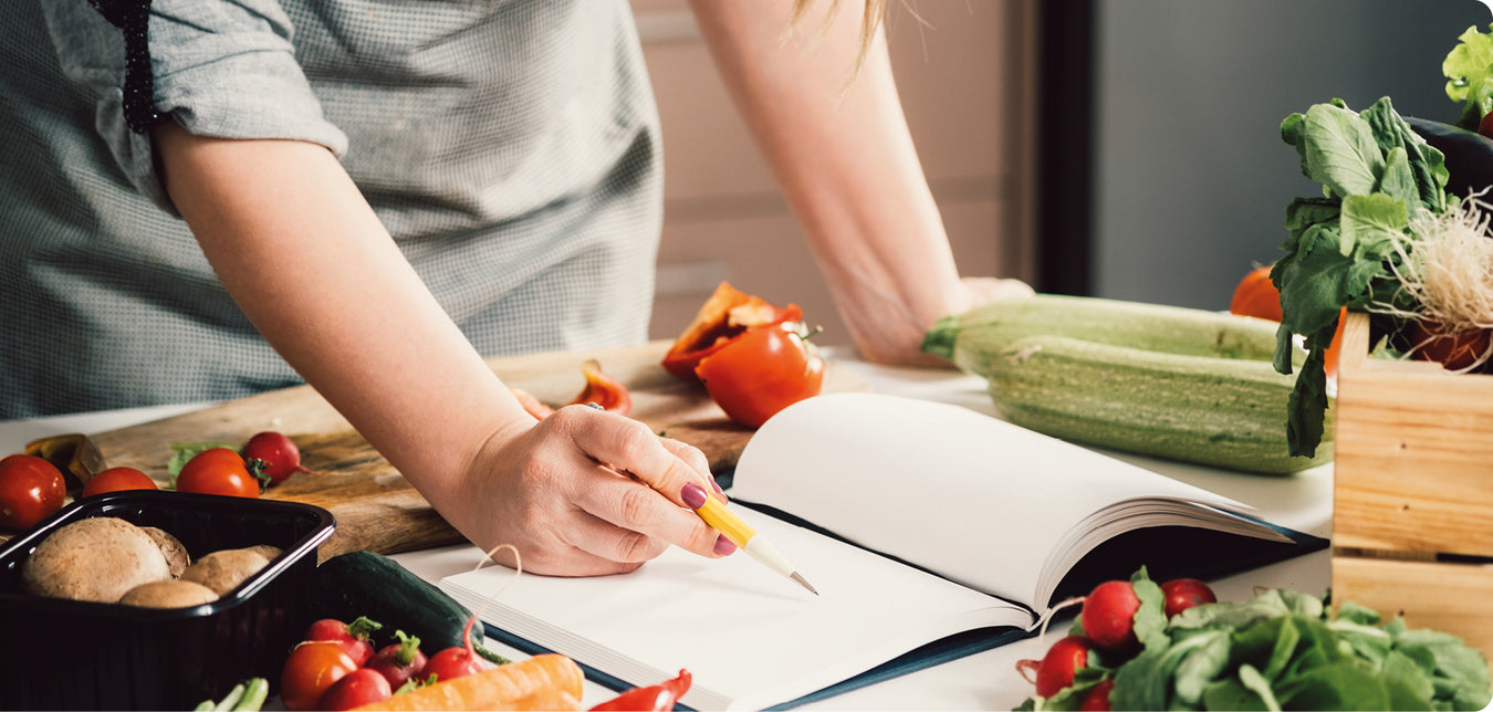 Frau schaut in ein Rezeptbuch, während sie kocht