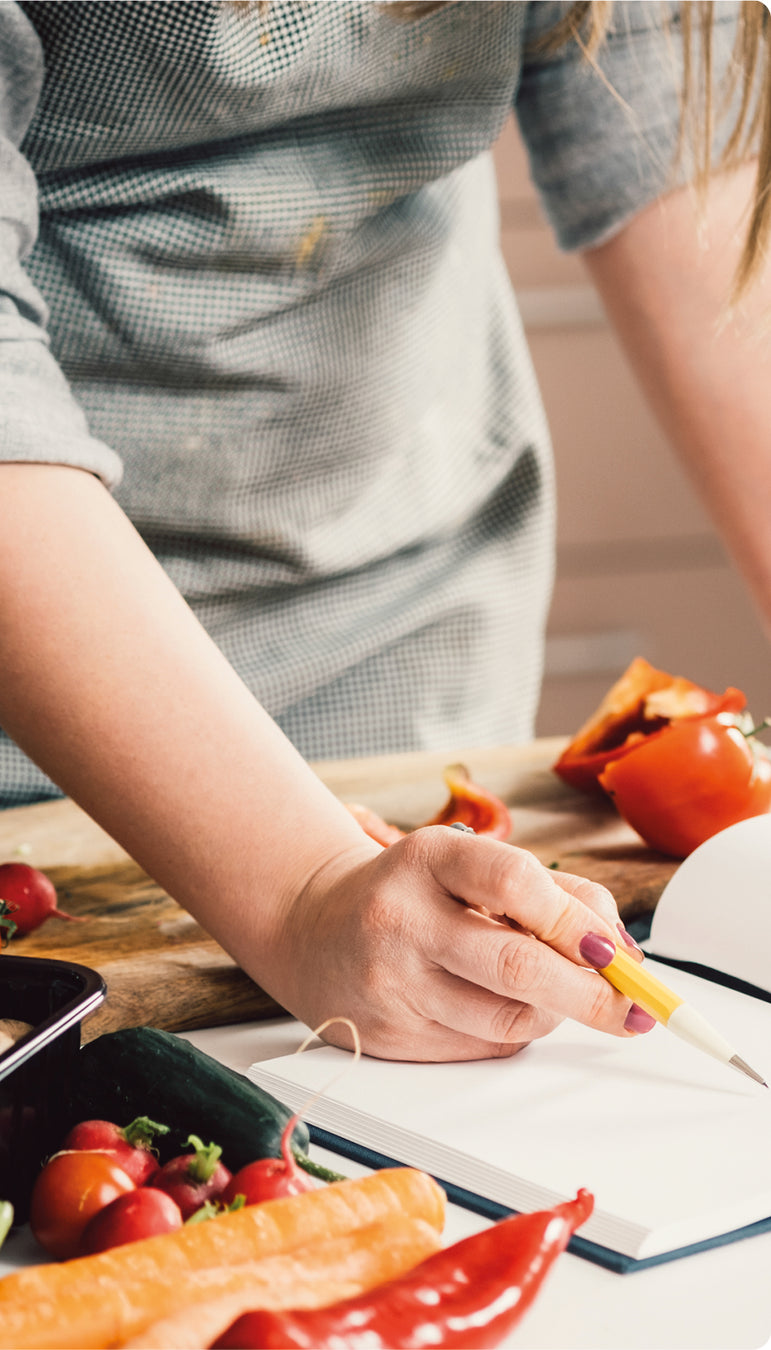 Frau schaut in ein Rezeptbuch, während sie kocht