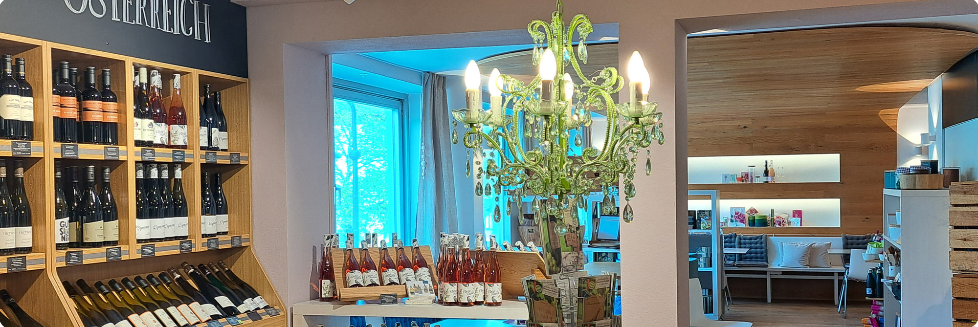 Blick aus der Weinabteilung in den Speiseraum von Mayr's Bistro mit einem Kronleuchter in der Mitte.