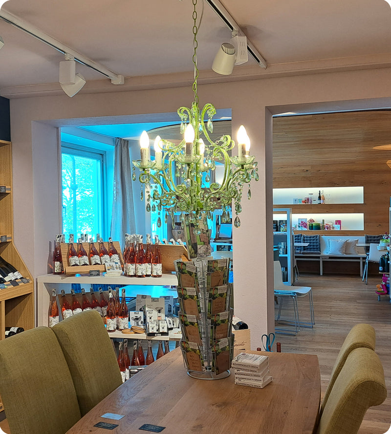 Blick aus der Weinabteilung in den Speiseraum von Mayr's Bistro mit einem Kronleuchter in der Mitte.