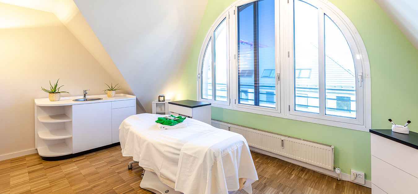 Behandlungsraum in Mayr's DaySpa Pasing mit einer Liege vor einem großzügigen Fenstern bei entspannender Atmosphäre