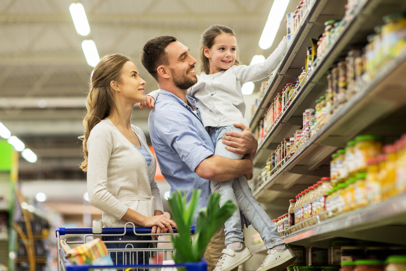 Eine Familie mit einem Kind beim Einkaufen im Reformhaus vor einem Regal. 