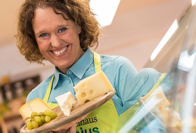 Mitarbeiterin präsentiert Käse auf einem Holzbrett